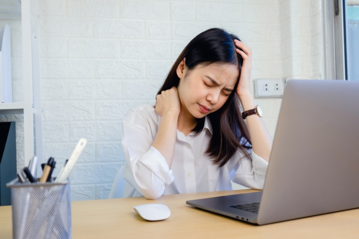 A woman experiences headache and neck pain at work