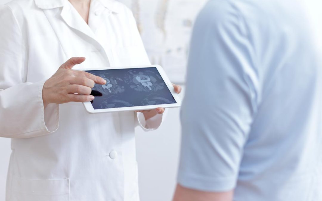 Doctor shows patient images of lumbar spine on a tablet